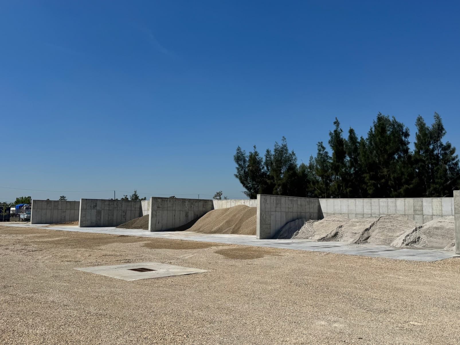 Gravel yard with concrete block walls under a clear blue sky