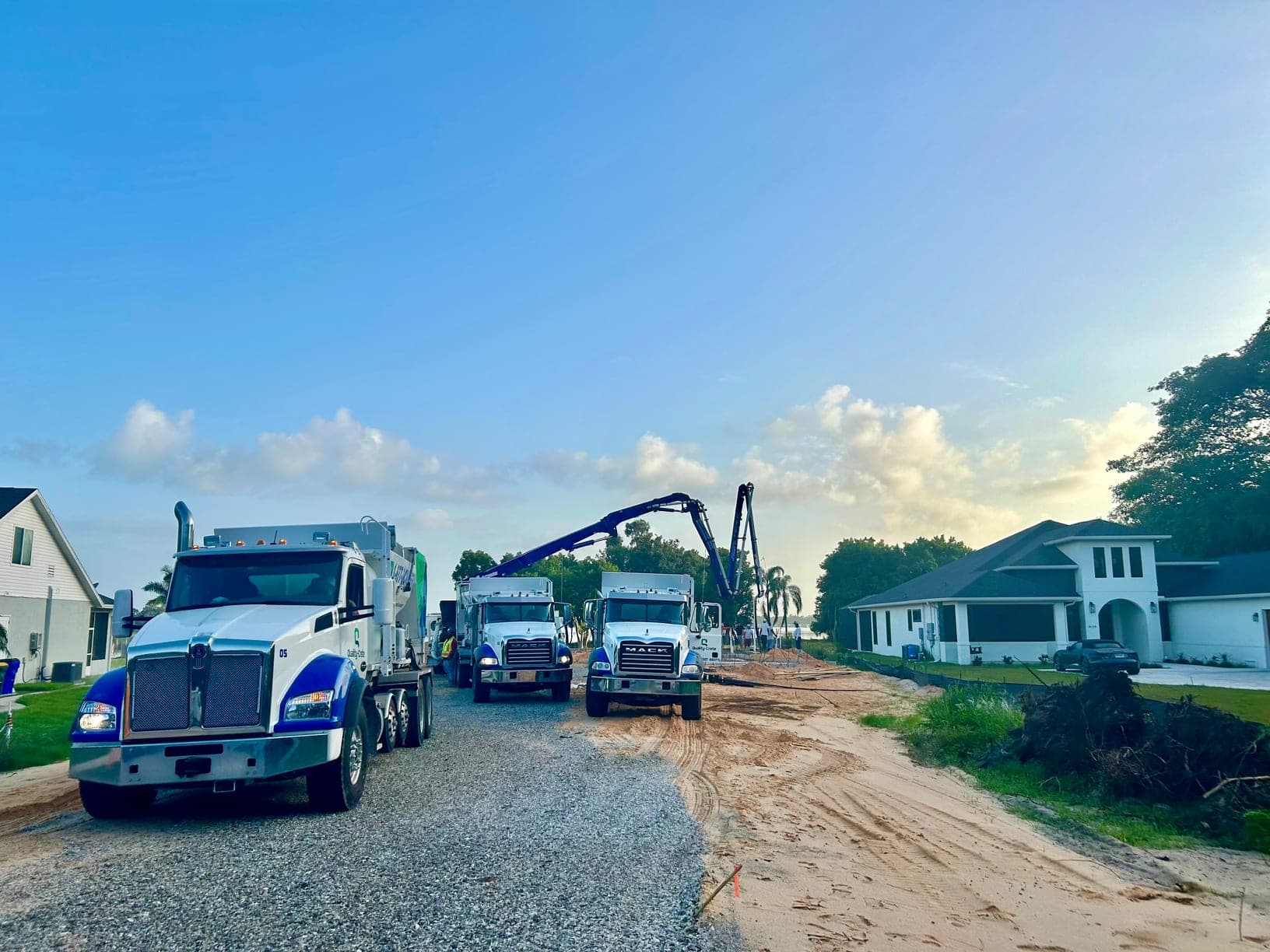 Quality-Crete mixer trucks and a concrete pump boom at a residential jobsite