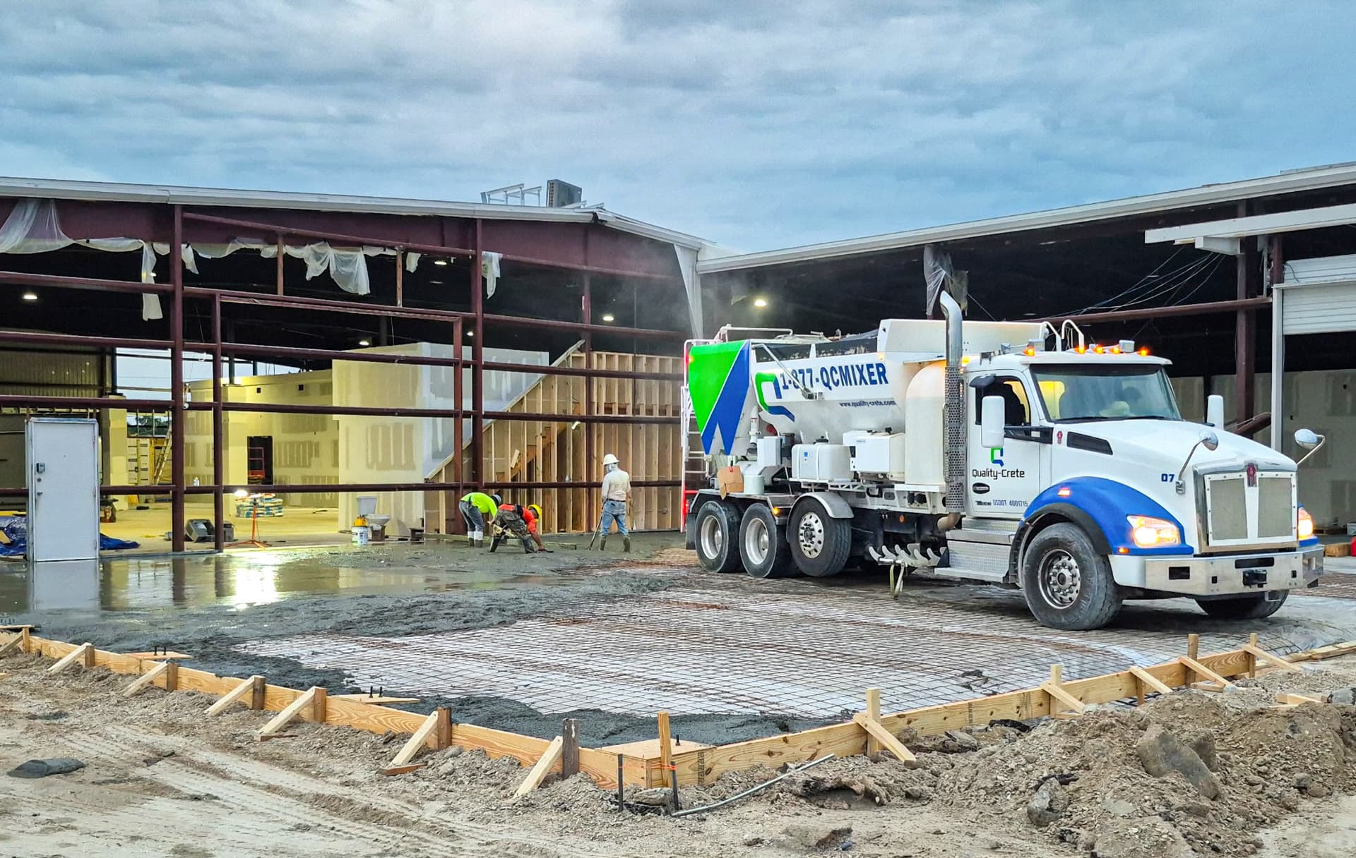 Crew screeding a large freshly poured concrete slab
