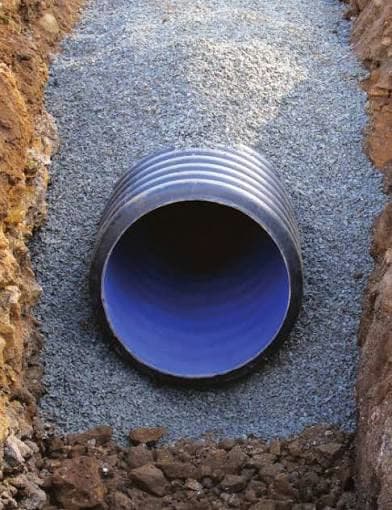 Corrugated pipe bedded in crushed stone in an open trench