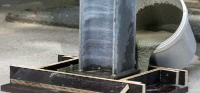 Grout poured from a chute around a steel column base within wood formwork
