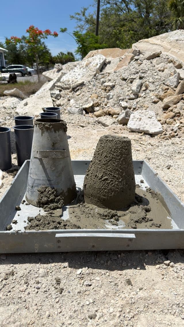Slump cone and slumped concrete sample on a test tray
