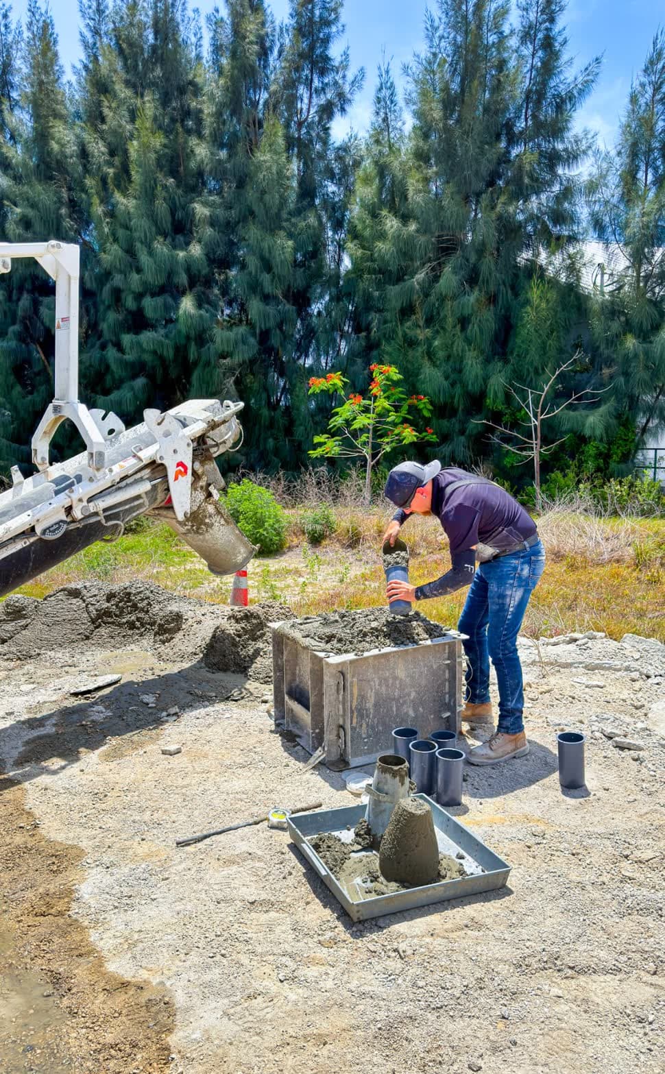 Technician filling test cylinders from a volumetric mixer chute beside a slump test