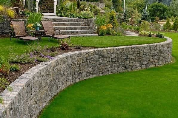 Curved stone retaining wall above a lawn