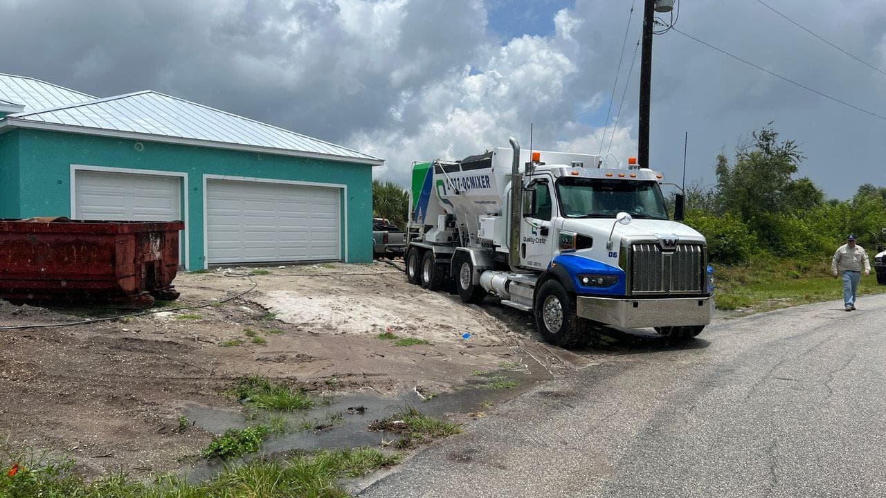 Quality-Crete volumetric mixer truck parked at a rural building site